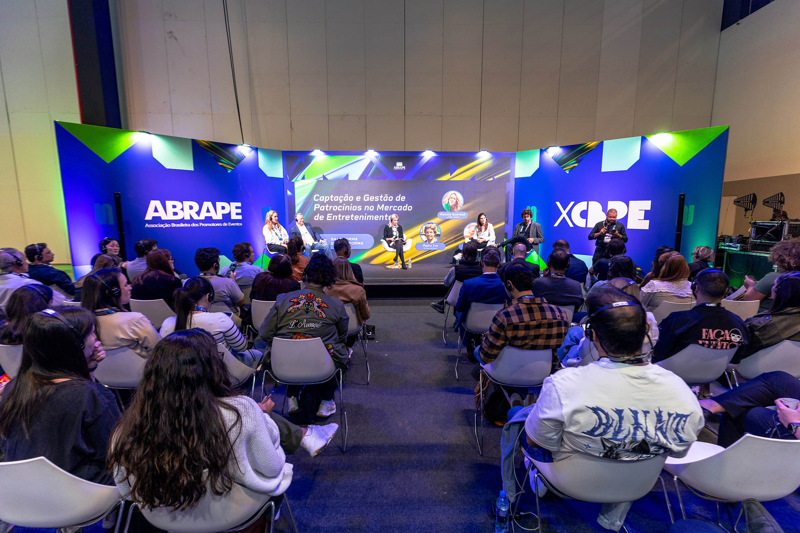 Palestrantes no palco do 10º CBPE diante da plateia, com os telões da ABRAPE